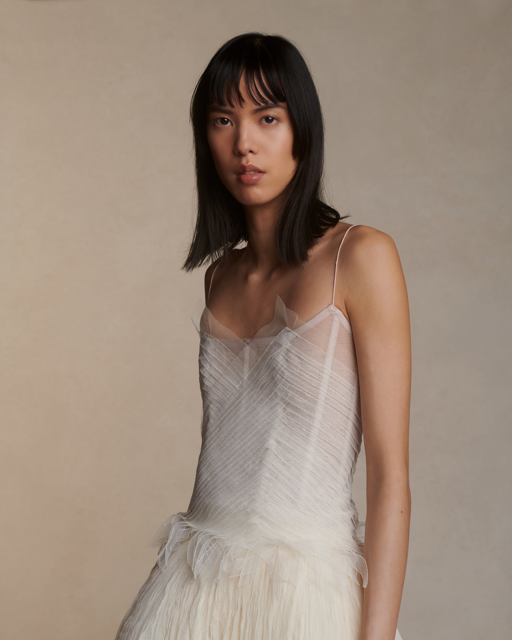 Camisole bustier top suspended by delicate spaghetti straps. Picot tulle ribbons criss cross across bodice, falling organically over hem. Boned corset revealed at center back. Center back zip closure.Styled with Theo SkirtStyled with Georgia Skirt