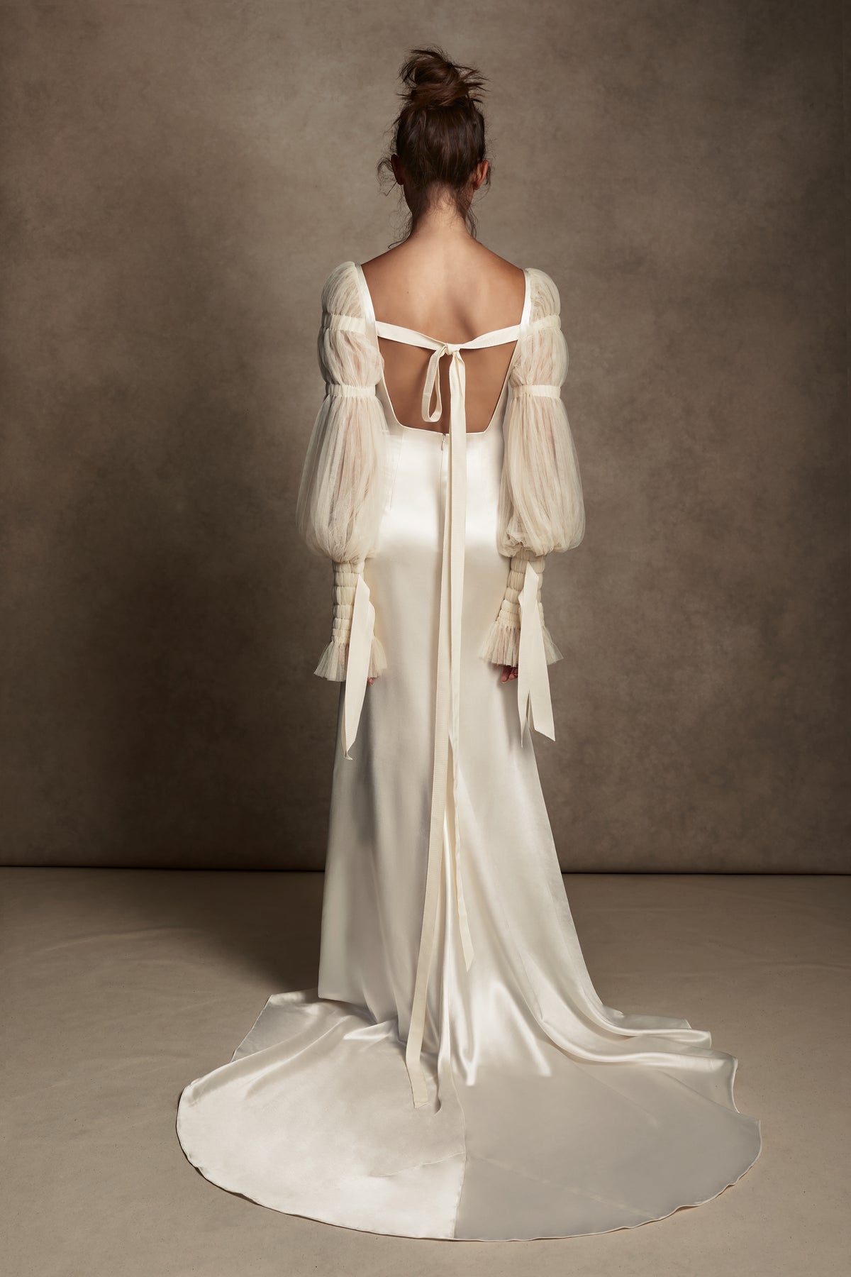 Silk Wool Satin gown with train. Pleated, delicate Tulle sleeves are gathered with Grosgrain detail.Styled with Flaired Baroque Pearl Drop Earrings 