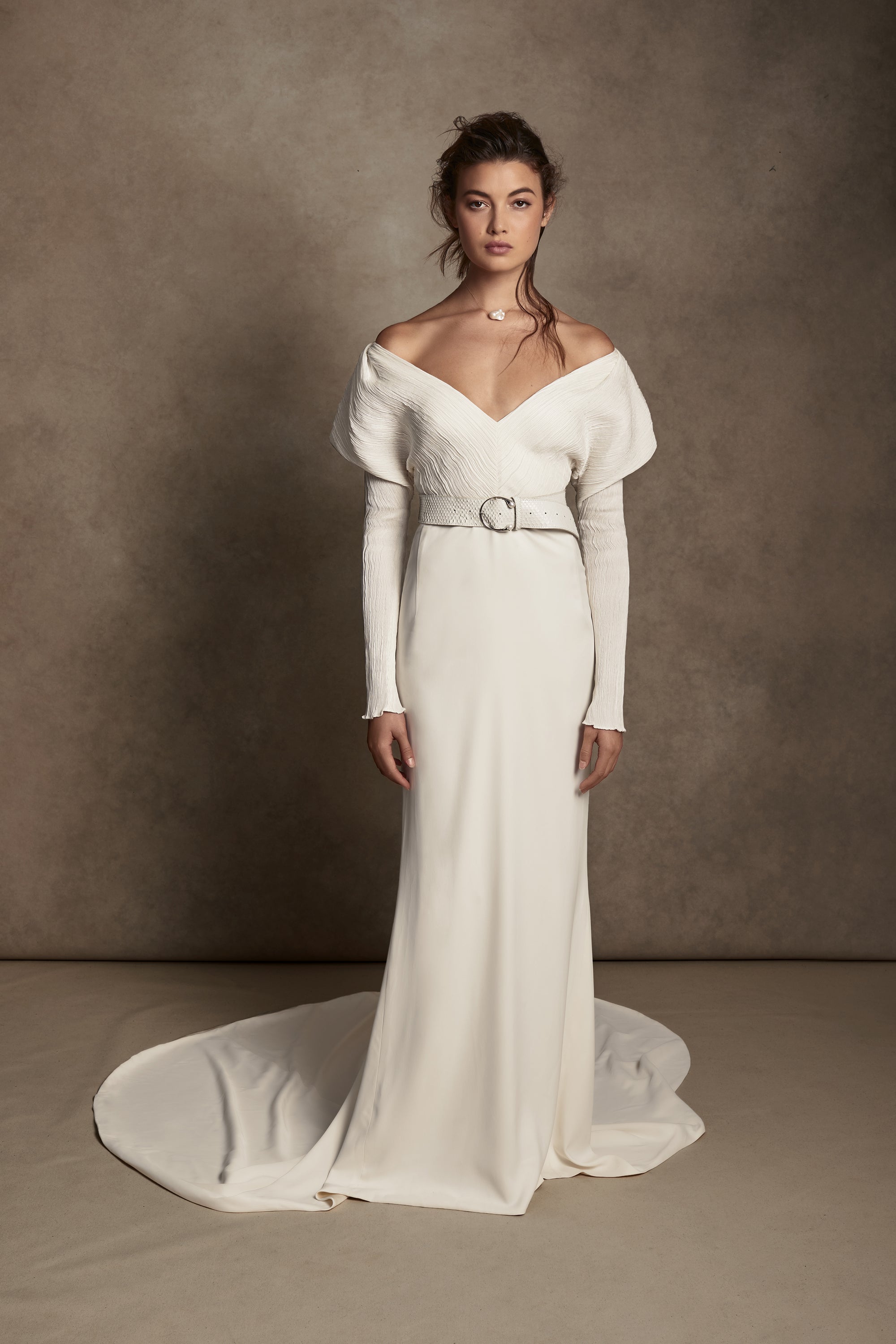 Off-shoulder gown with mini-pleated Georgette draped sleeves, and Grosgrain waist detail. Smooth faced Cady skirt, with circular train.Styled with Charlotte Skirt, Python Belt with Pearl Buckle and Flaired Baroque Pearl Drop Earrings.