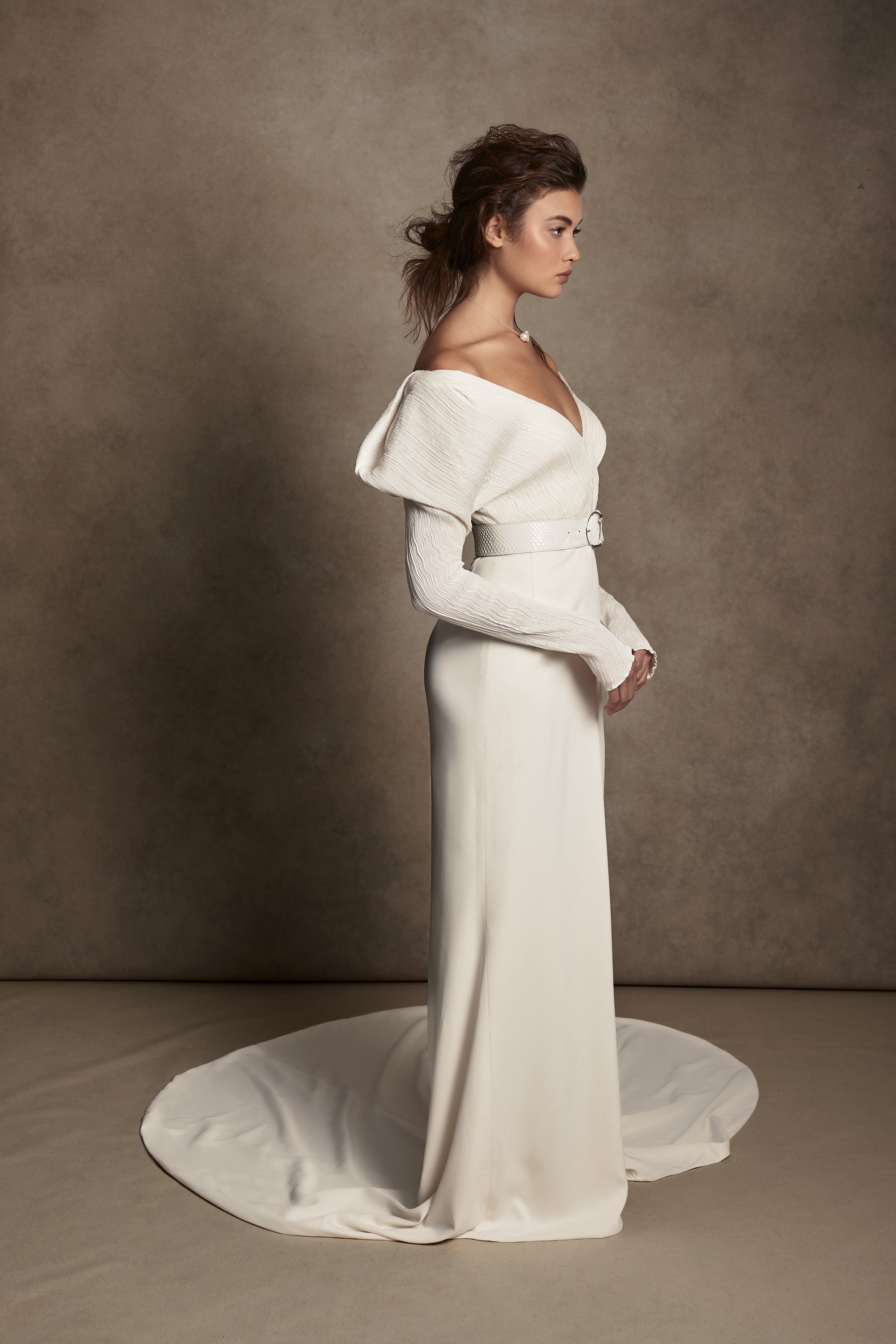 Off-shoulder gown with mini-pleated Georgette draped sleeves, and Grosgrain waist detail. Smooth faced Cady skirt, with circular train.Styled with Charlotte Skirt, Python Belt with Pearl Buckle and Flaired Baroque Pearl Drop Earrings.
