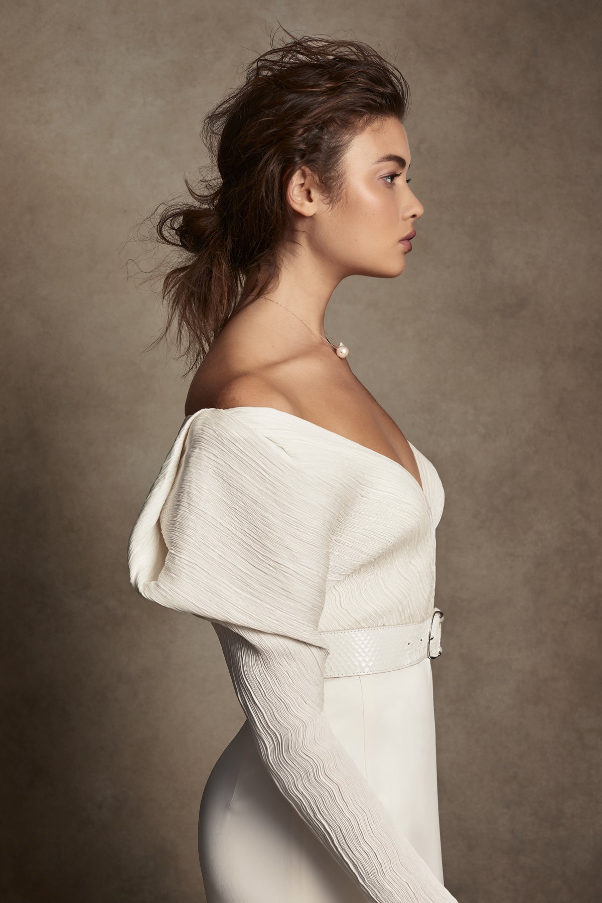 Off-shoulder gown with mini-pleated Georgette draped sleeves, and Grosgrain waist detail. Smooth faced Cady skirt, with circular train.Styled with Charlotte Skirt, Python Belt with Pearl Buckle and Flaired Baroque Pearl Drop Earrings.