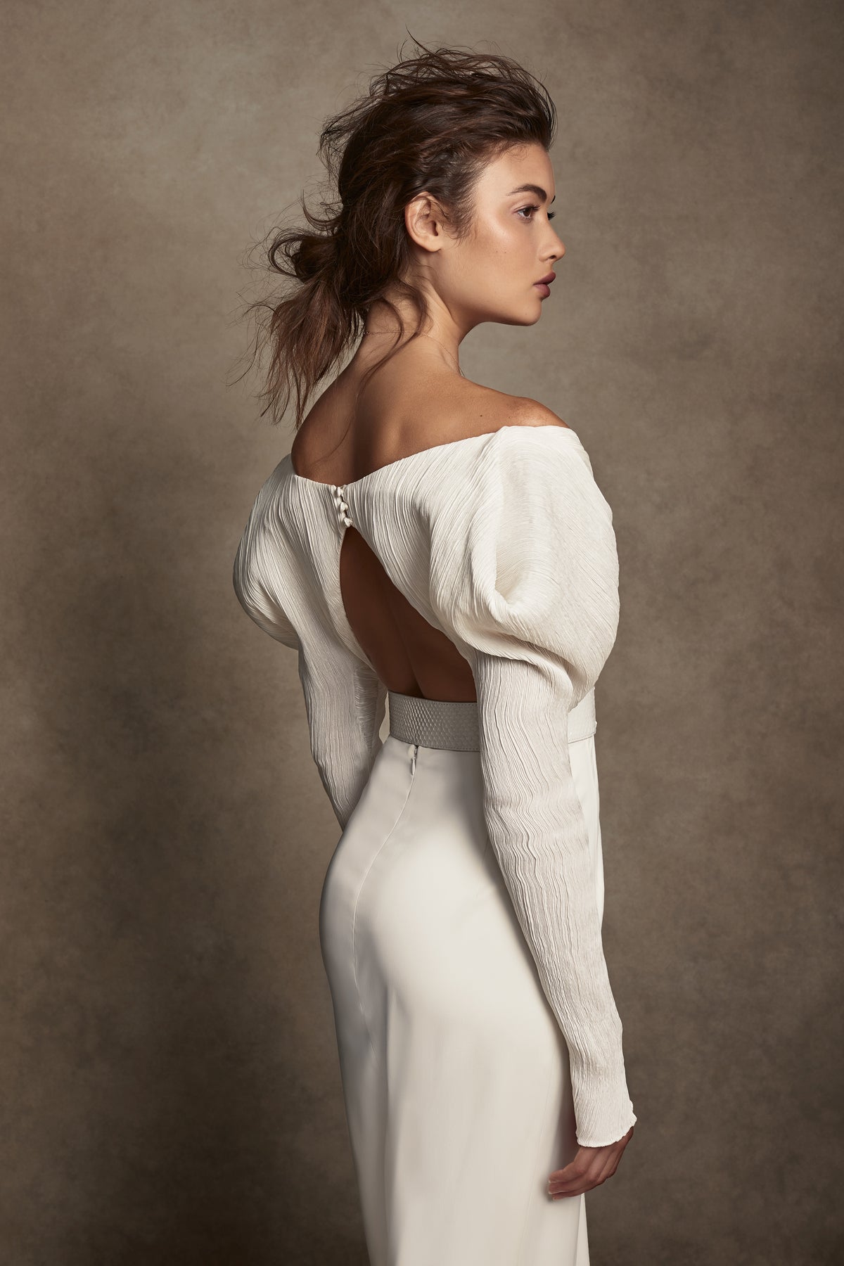 Off-shoulder gown with mini-pleated Georgette draped sleeves, and Grosgrain waist detail. Smooth faced Cady skirt, with circular train.Styled with Charlotte Skirt, Python Belt with Pearl Buckle and Flaired Baroque Pearl Drop Earrings.