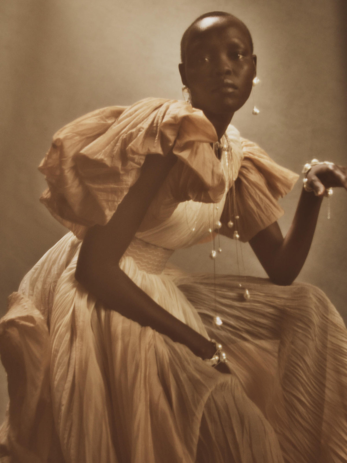 Dip dyed pleated paper organza gown with bubble hem and voluminous short ruffled sleeve. Center back zipper and external grosgrain belt atop soft tulle lined internal bustier. Crew neckline with button close at back of neck creating triangular shaped open back. Available in ivory upon request.