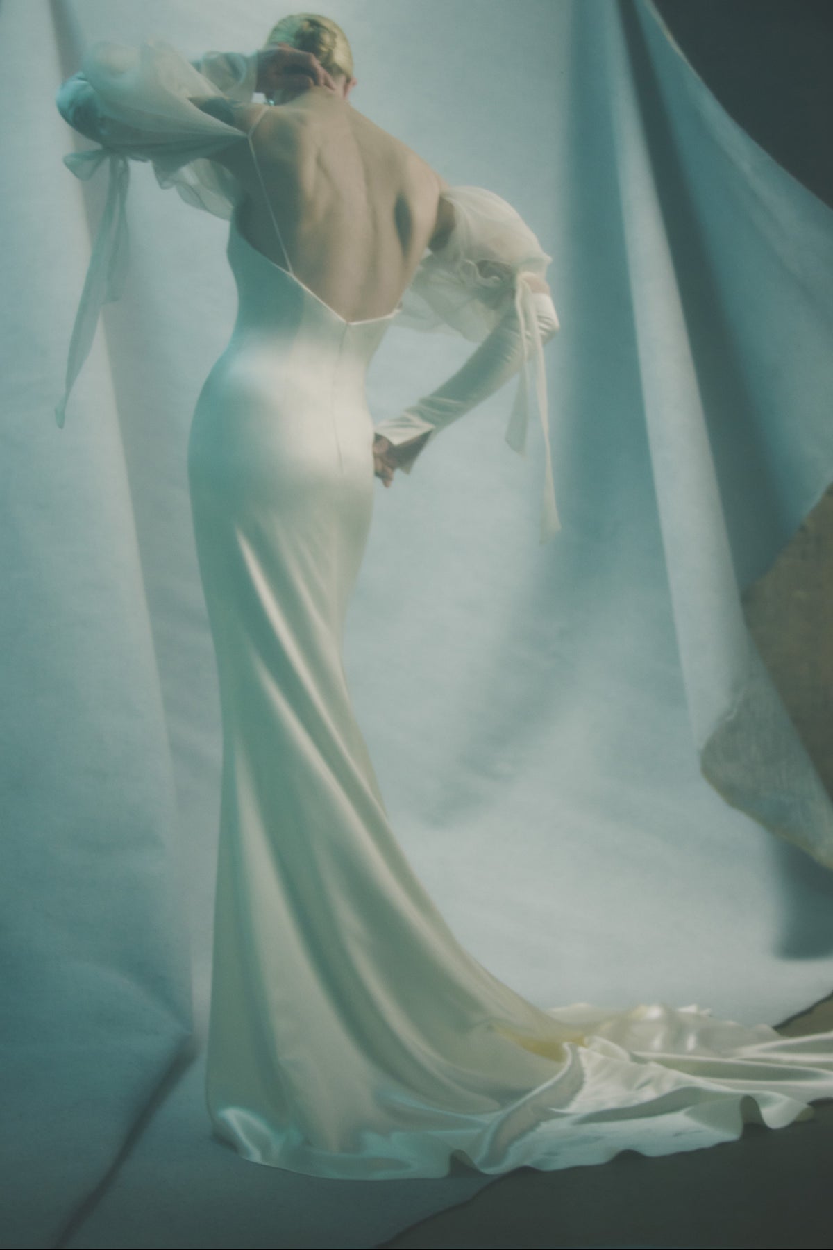 Silk wool gown with contrasting billowed gauze sleeve. Breathable silk charmeuse sleeve with 5 inch slit at inner wrist and decorative ties at elbow. Darts at bust for shaping and internal bustier with side boning, cups, grosgrain belt with 3 hook position, and external center back zip. Fully lined.
