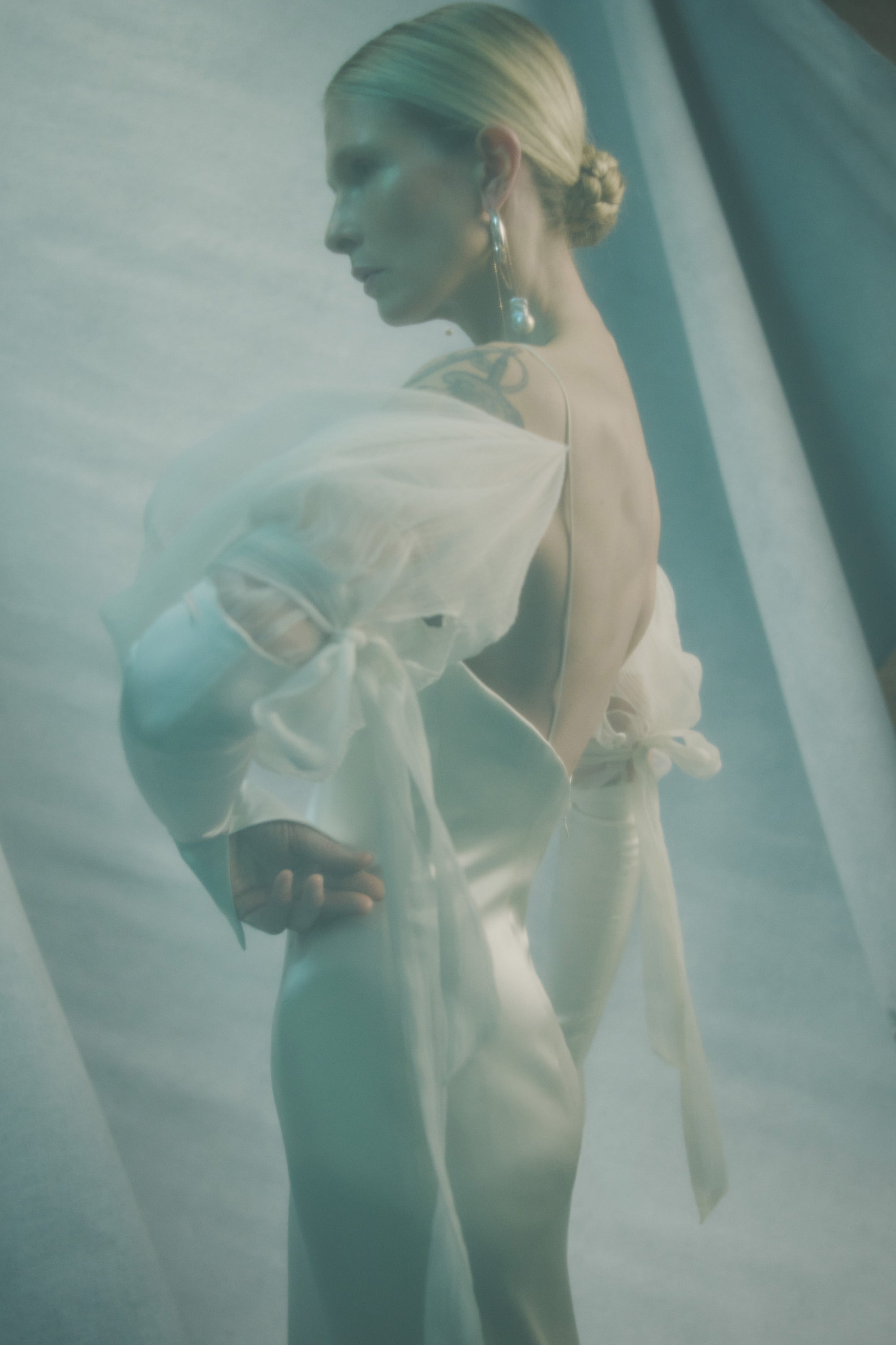 Silk wool gown with contrasting billowed gauze sleeve. Breathable silk charmeuse sleeve with 5 inch slit at inner wrist and decorative ties at elbow. Darts at bust for shaping and internal bustier with side boning, cups, grosgrain belt with 3 hook position, and external center back zip. Fully lined.