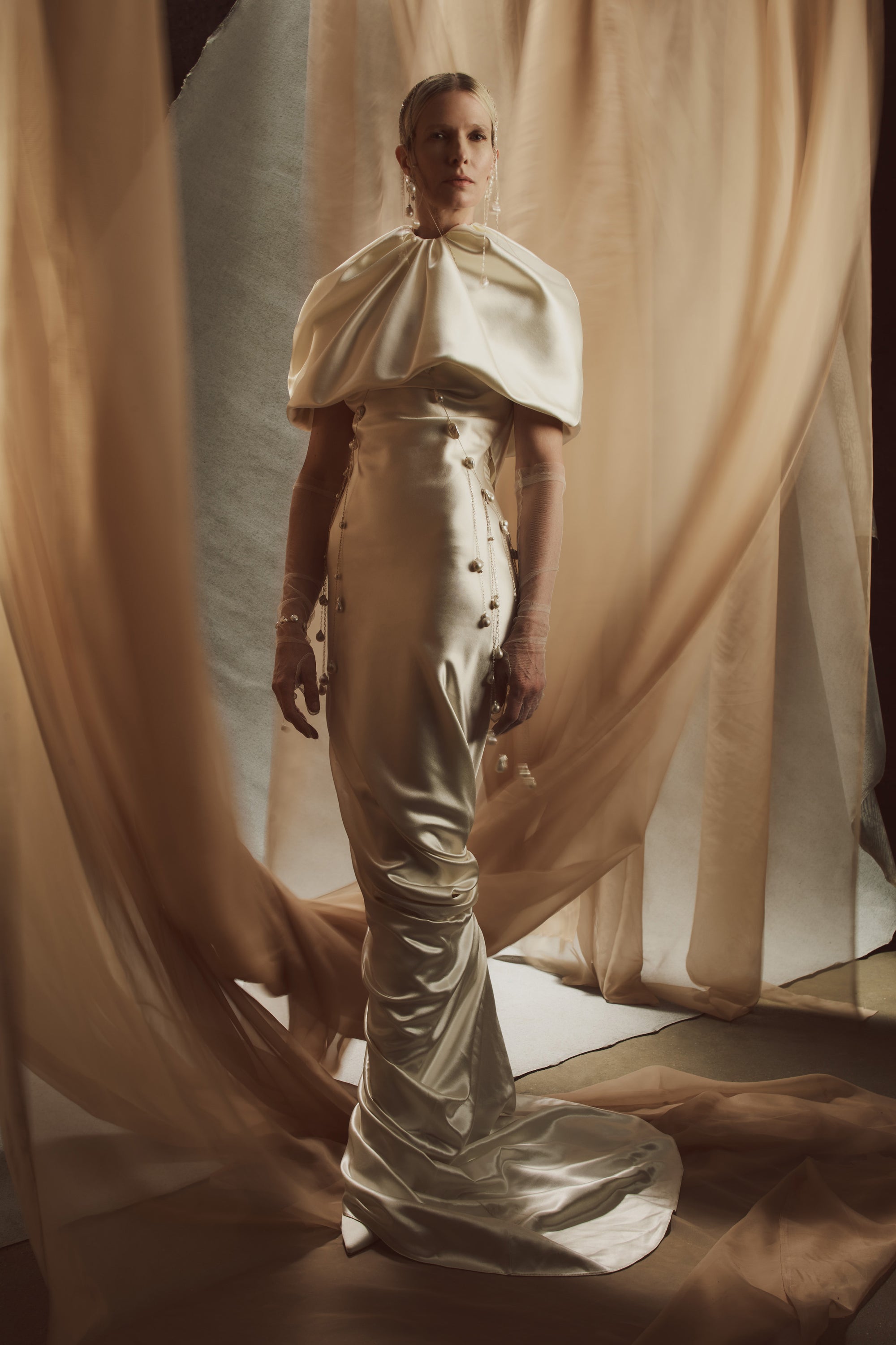 Raised cowl neck, bias cut silk wool sleeveless gown. Open back with scarf draped accent. Fully lined with side zip closure.Styled with Rebecca lace bolero