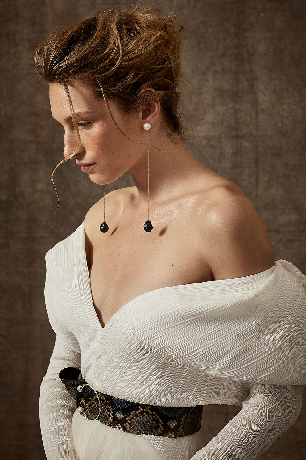 Off-shoulder gown with mini-pleated Georgette draped sleeves, and Grosgrain waist detail. Smooth faced Cady skirt, with circular train.Styled with Charlotte Skirt, Python Belt with Pearl Buckle and Flaired Baroque Pearl Drop Earrings.