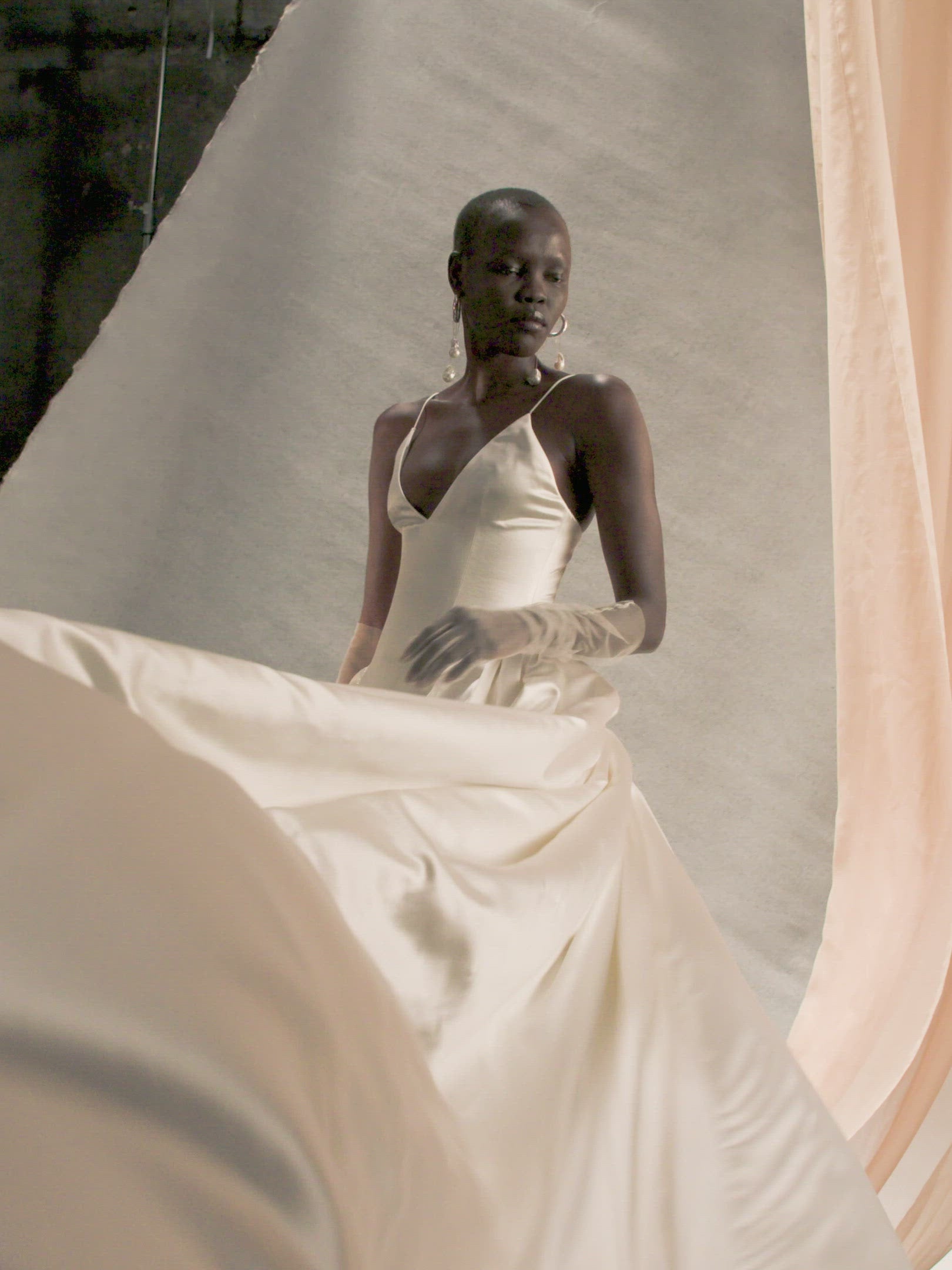 Deep V neck cathedral length gown with shirred, full skirt and elongated basque waist. Self lined, boned bodice for structure, and darts for shaping. Internal grosgrain waistband belt with three positions and center back zip. Fully lined soft skirt with exaggerated train, can can ruffle at hip for volume and structure.