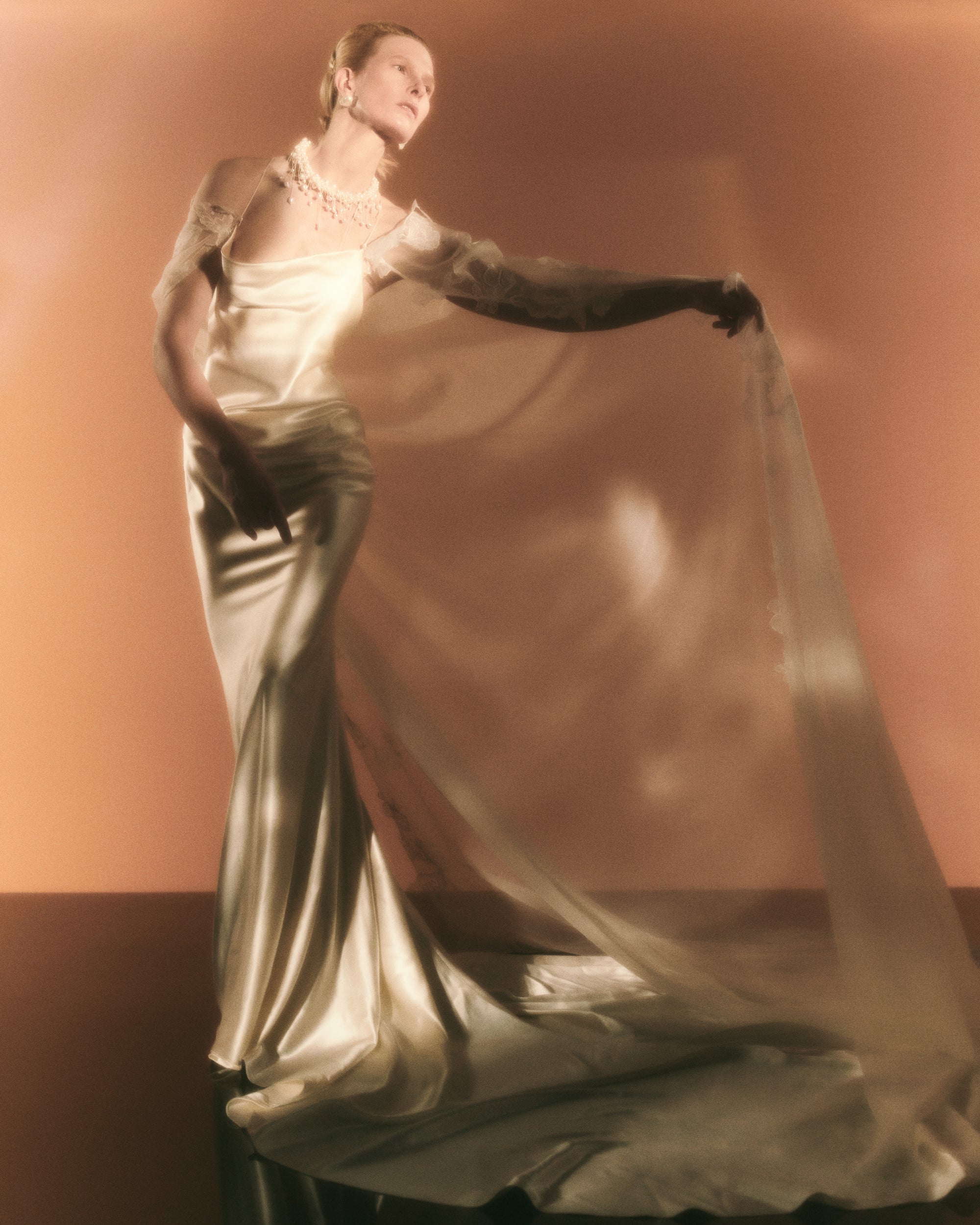 Cowled neck, crepe back satin slip gown. Low scooped back with cross back spaghetti straps. Detachable tulle cape with hand appliquéd chantilly lace edging along sides. Center back zip, hook and eye closure.