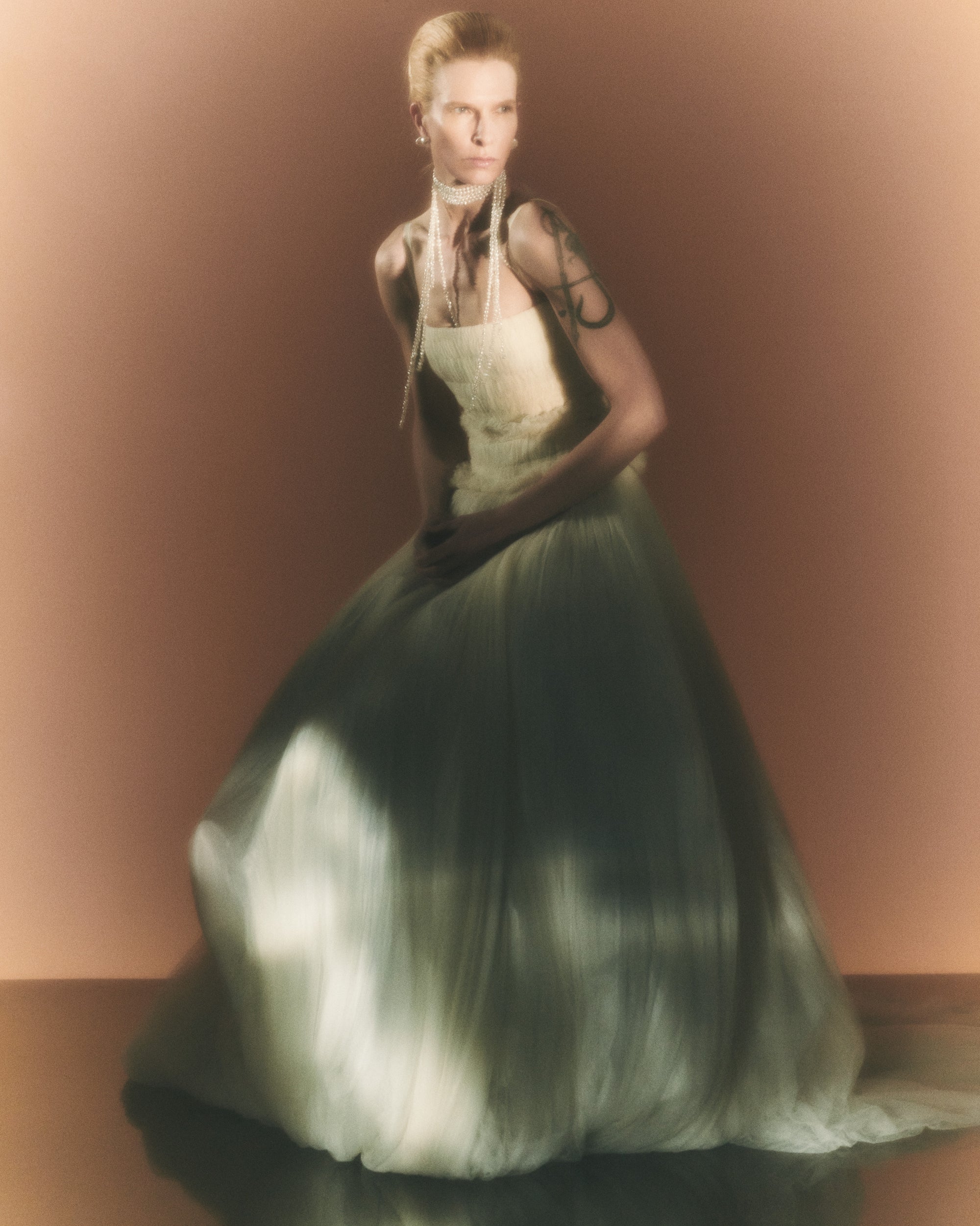 Soft tulle smocked and collapsed ballgown. Tightly gathered pleating along corseted, drop waist bodice. Grosgrain straps connecting to soft v-back. Sunburst pleated soft tulle over crinoline enclosed, bubbled taffeta skirt. Boning through body and center back zip close.