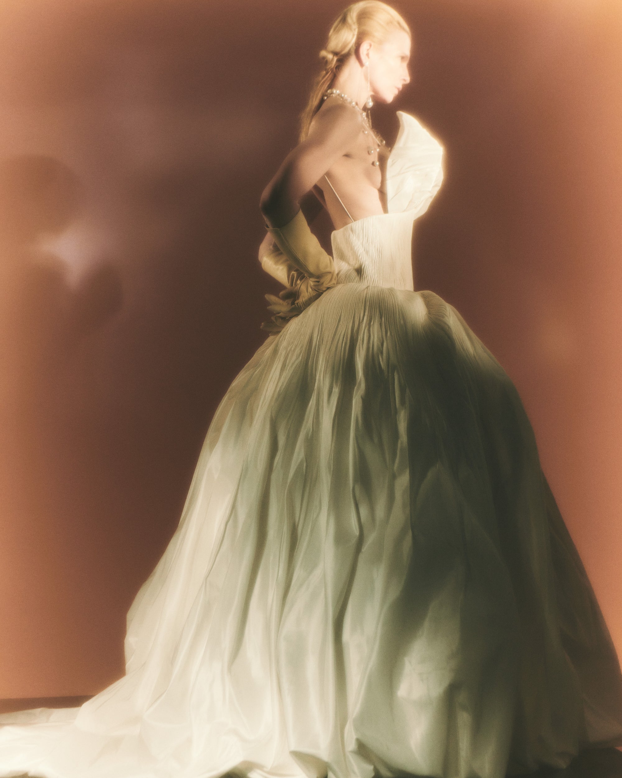 Micro-tucked silk taffeta ballgown. Crinoline enclosed, bubbled skirt with extended train. Soft triangular cups for support beneath abstract triangular draped taffeta panels. Soft boning for structure and center back close. The belt is sold separately.